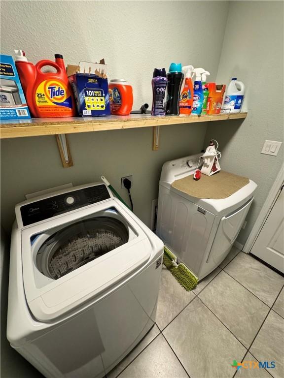 laundry area with washer and clothes dryer and light tile patterned floors