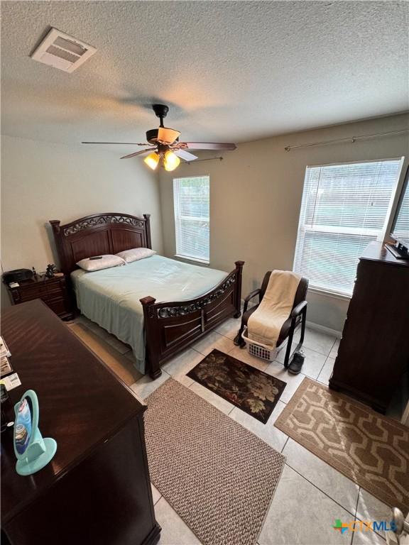 tiled bedroom featuring a textured ceiling and ceiling fan