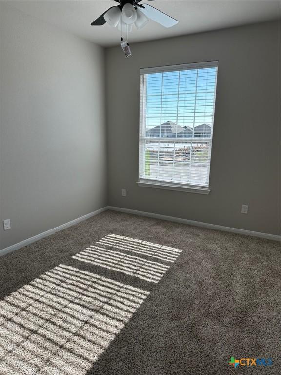 spare room featuring carpet, ceiling fan, and baseboards