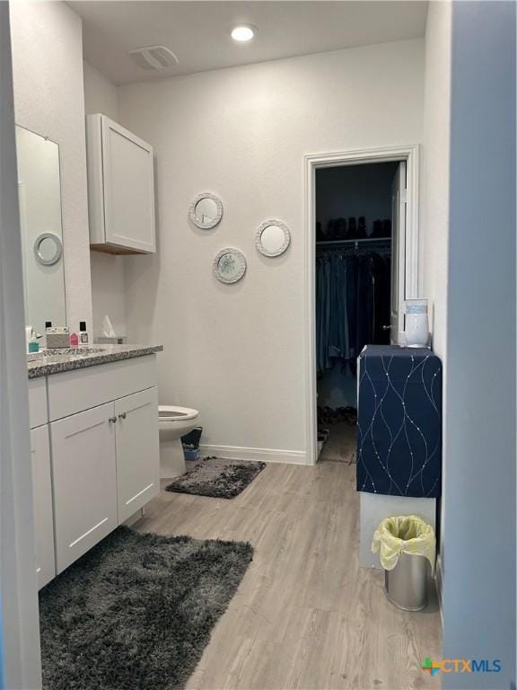 bathroom featuring vanity, wood-type flooring, and toilet