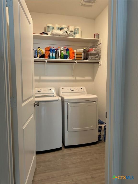 laundry area featuring washer and clothes dryer and light hardwood / wood-style flooring