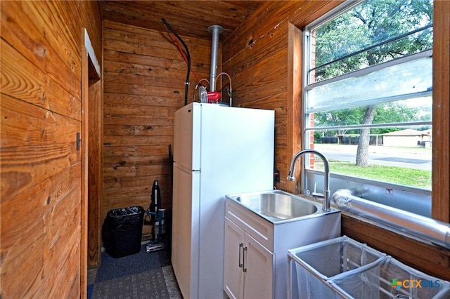 929 E Cedar St, Seguin, TX 78155 - kitchen featuring freestanding refrigerator, wooden walls, white cabinets, and light countertops