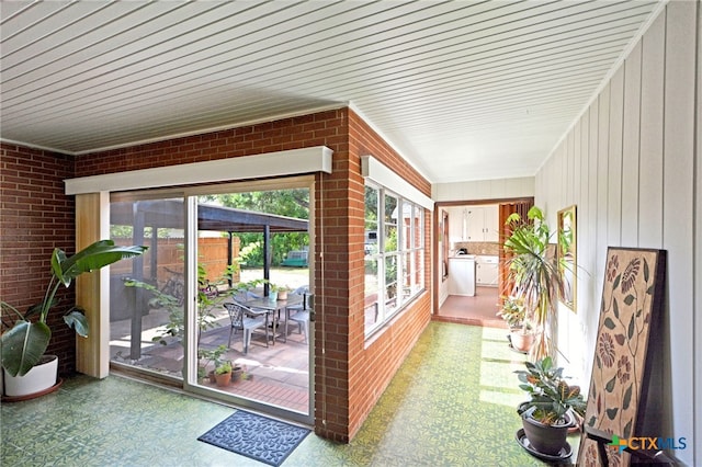 929 E Cedar St, Seguin, TX 78155 - unfurnished sunroom featuring tile patterned floors, brick wall, and wooden walls