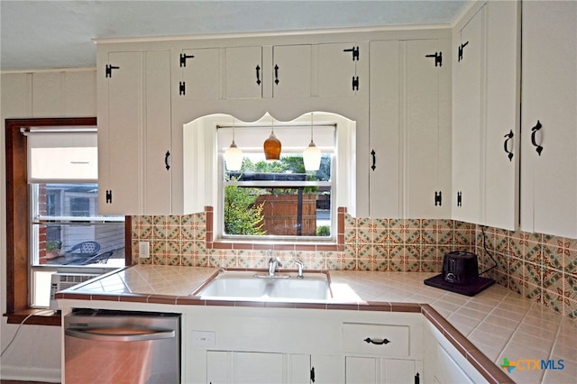 929 E Cedar St, Seguin, TX 78155 - kitchen with stainless steel dishwasher, tile countertops, white cabinetry, and backsplash