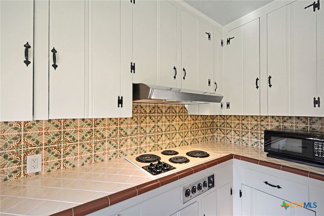 929 E Cedar St, Seguin, TX 78155 - kitchen featuring under cabinet range hood, black microwave, white electric cooktop, and white cabinets