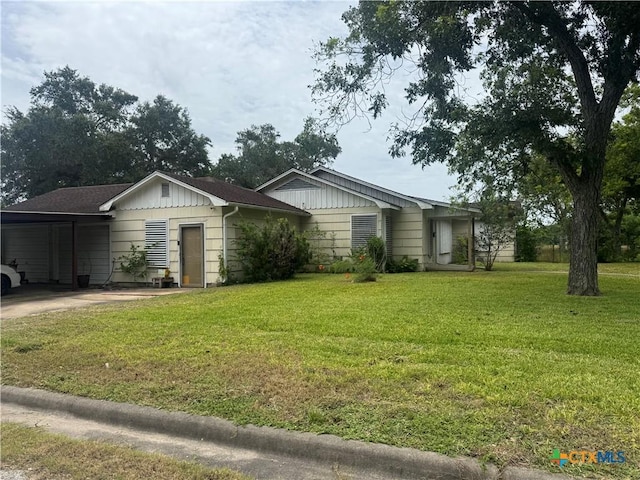 308 Avenue E Ave E, Victoria, TX 77901 - view of front of house featuring board and batten siding, a front yard, a carport, and driveway