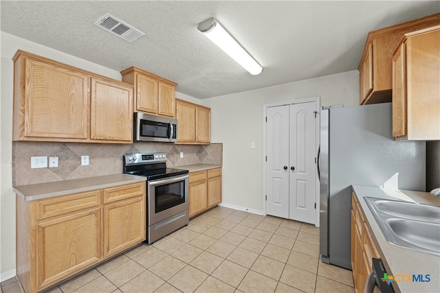 kitchen featuring decorative backsplash, sink, light tile patterned floors, and stainless steel appliances