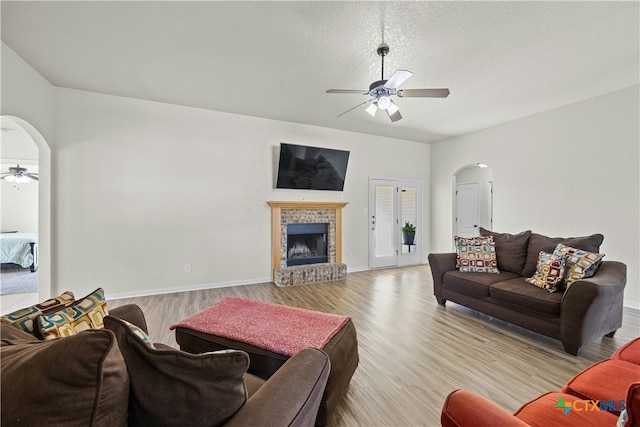 living room featuring a textured ceiling, light hardwood / wood-style floors, and ceiling fan