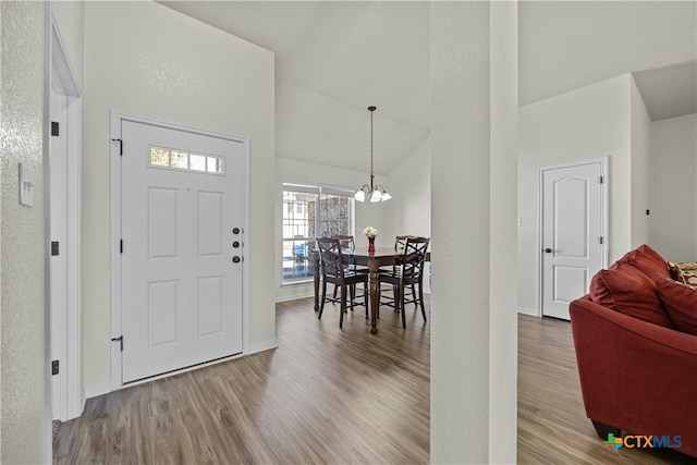 entryway featuring a chandelier, hardwood / wood-style flooring, and high vaulted ceiling