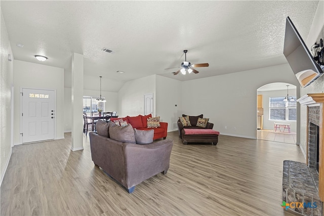 living room with a brick fireplace, ceiling fan, plenty of natural light, and light hardwood / wood-style flooring