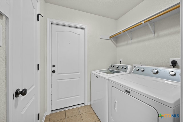 laundry room with washing machine and dryer, light tile patterned floors, and a textured ceiling