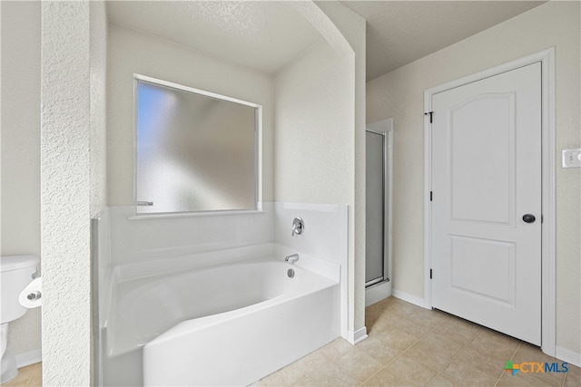 bathroom featuring tile patterned flooring, a textured ceiling, toilet, and separate shower and tub