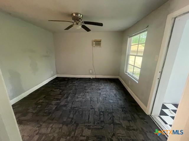 spare room with ceiling fan, a wall mounted air conditioner, and baseboards