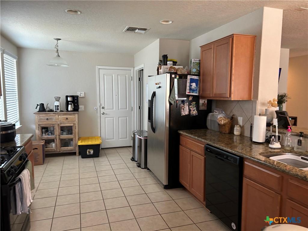 21934 Ruby Run, San Antonio, TX 78259 - kitchen featuring black appliances, light tile patterned flooring, brown cabinets, a sink, and a textured ceiling