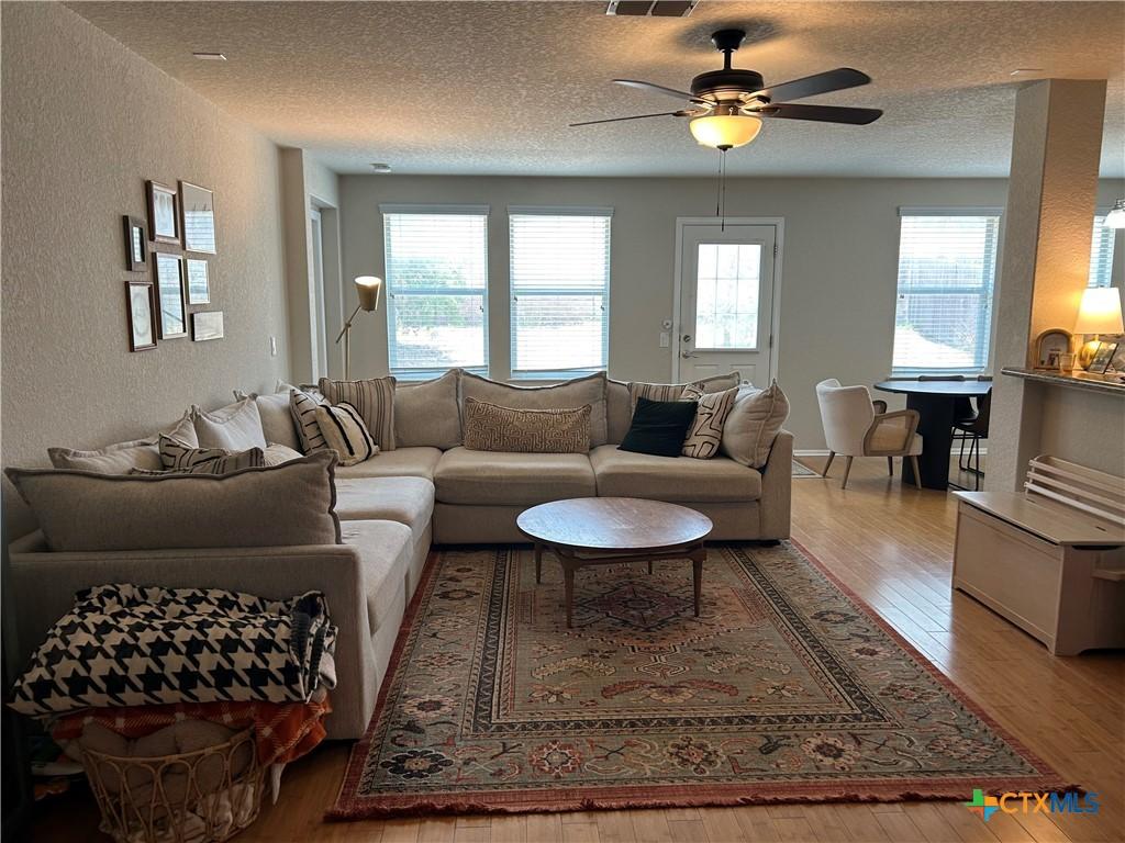 21934 Ruby Run, San Antonio, TX 78259 - living area featuring a textured wall, a textured ceiling, wood finished floors, and ceiling fan