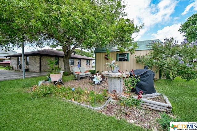 view of front of house featuring an outdoor structure, a front lawn, and a patio