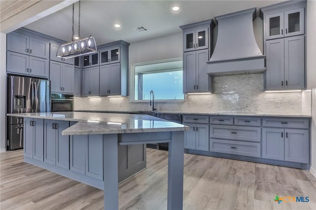 916 Stone Rd, Temple, TX 76501 - kitchen featuring custom range hood, black oven, stainless steel refrigerator with ice dispenser, a kitchen island, and light wood-type flooring