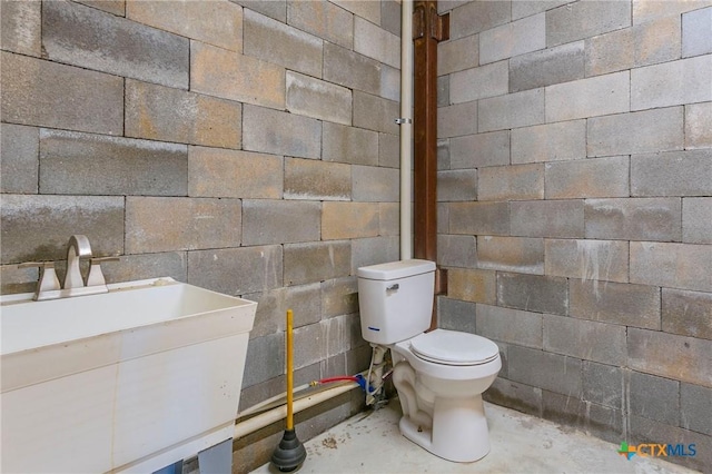 916 Stone Rd, Temple, TX 76501 - half bathroom with a sink, unfinished concrete floors, concrete block wall, and toilet