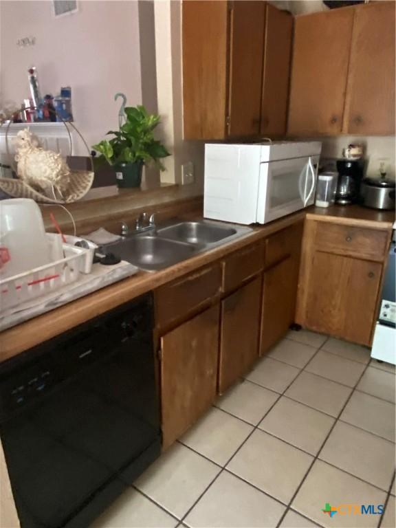 1318 Deupree Dr, Austin, TX 78753 - kitchen featuring black dishwasher, white microwave, a sink, and light tile patterned floors