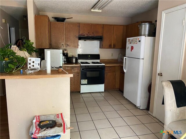 1318 Deupree Dr, Austin, TX 78753 - kitchen with freestanding refrigerator, range with gas stovetop, range hood, brown cabinets, and a textured ceiling