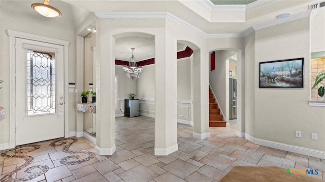 foyer entrance featuring ornamental molding, a chandelier, and a tray ceiling