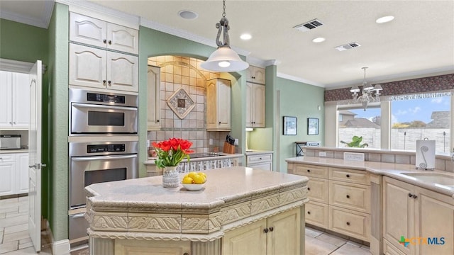 kitchen featuring a center island, a notable chandelier, hanging light fixtures, crown molding, and sink