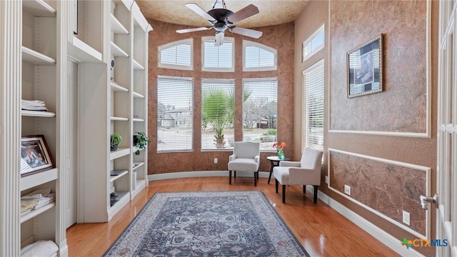 living area with ceiling fan, built in features, and light hardwood / wood-style flooring