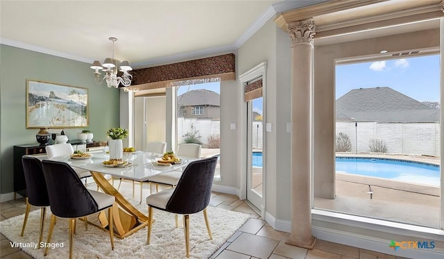 tiled dining room featuring an inviting chandelier, ornamental molding, and decorative columns