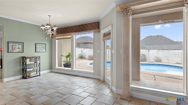 doorway featuring crown molding, a chandelier, and ornate columns