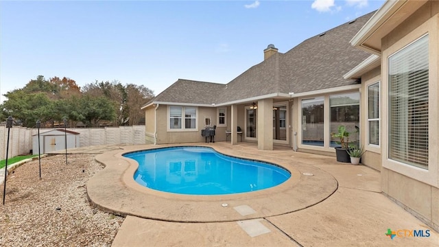 view of swimming pool with a patio and a storage unit