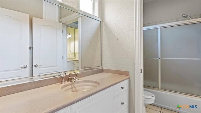 full bathroom featuring toilet, combined bath / shower with glass door, tile patterned flooring, and vanity