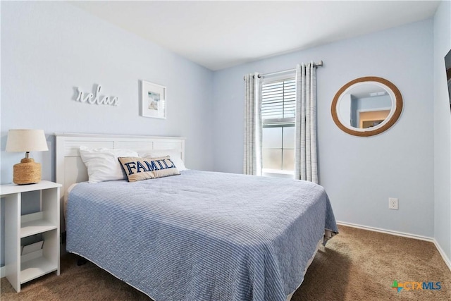 bedroom featuring baseboards and dark carpet