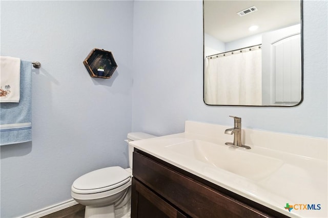 full bath featuring visible vents, toilet, vanity, and baseboards