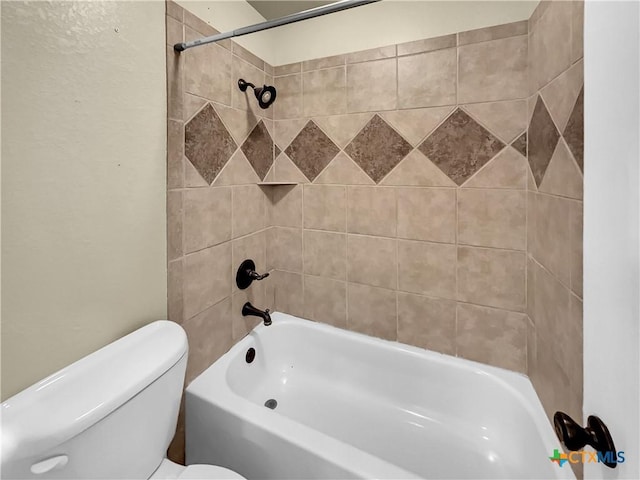 bathroom featuring tiled shower / bath combo and toilet