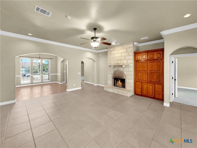 unfurnished living room featuring a stone fireplace, light tile patterned flooring, ceiling fan with notable chandelier, and ornamental molding