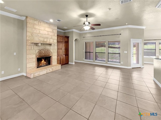 unfurnished living room with a fireplace, ceiling fan, ornamental molding, and light tile patterned flooring