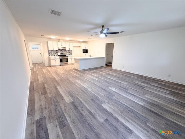 unfurnished living room featuring ceiling fan, sink, and light hardwood / wood-style flooring