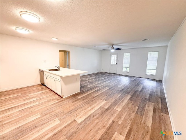 kitchen with white cabinetry, kitchen peninsula, stainless steel dishwasher, light hardwood / wood-style flooring, and sink