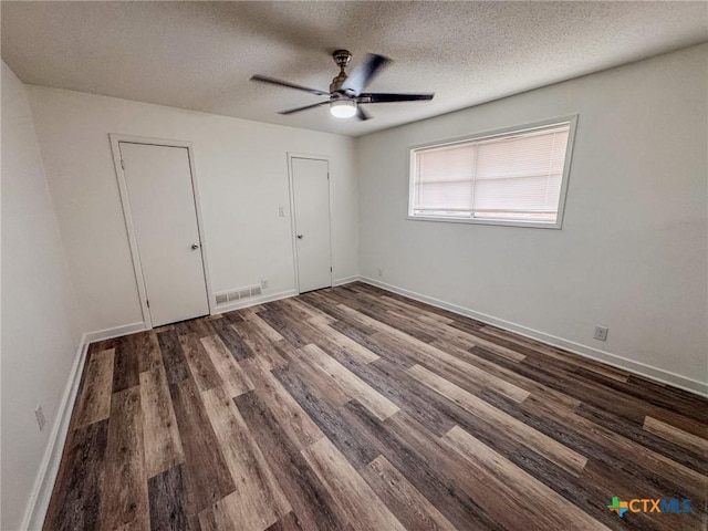 unfurnished bedroom featuring ceiling fan, a textured ceiling, and dark hardwood / wood-style floors