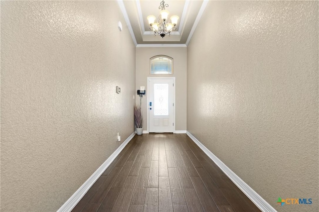 doorway featuring ornamental molding, dark wood-type flooring, and an inviting chandelier