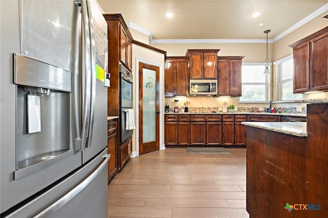 kitchen featuring pendant lighting, ornamental molding, appliances with stainless steel finishes, and light hardwood / wood-style flooring