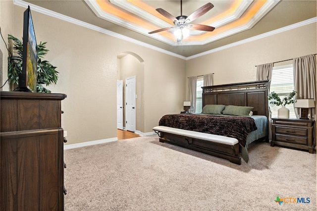 bedroom featuring a raised ceiling, crown molding, light carpet, and ceiling fan