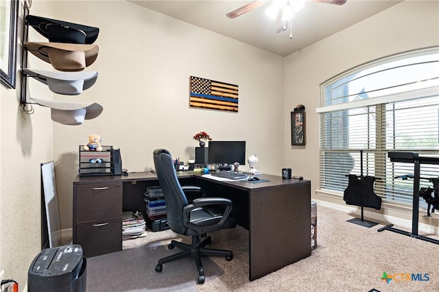 carpeted home office featuring ceiling fan