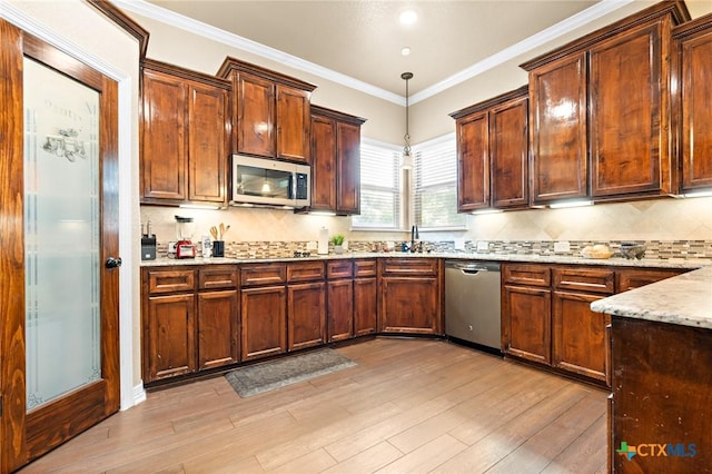 kitchen featuring crown molding, appliances with stainless steel finishes, light stone counters, light hardwood / wood-style floors, and decorative light fixtures