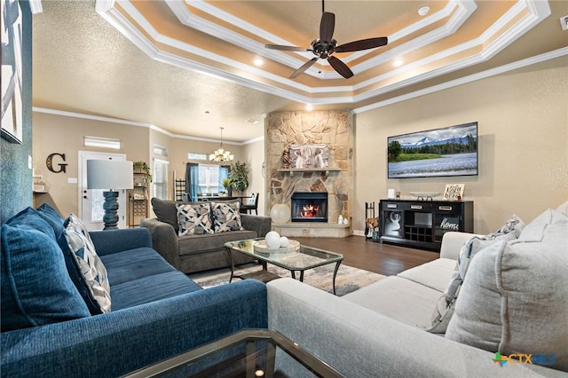 living room featuring a textured ceiling, ornamental molding, dark hardwood / wood-style flooring, a tray ceiling, and a fireplace