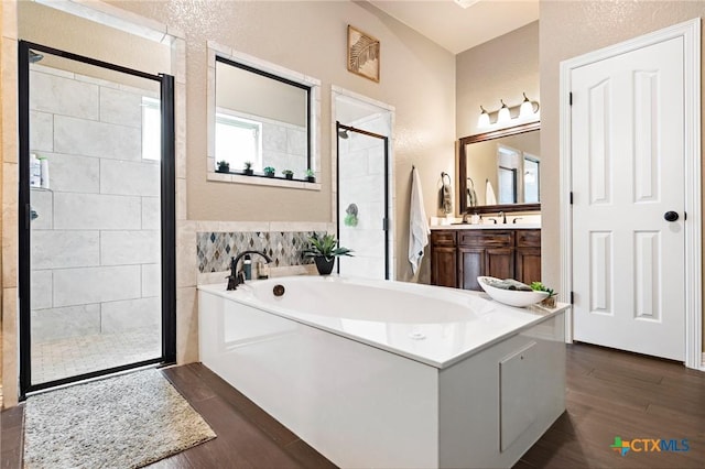 bathroom with shower with separate bathtub, hardwood / wood-style floors, and vanity