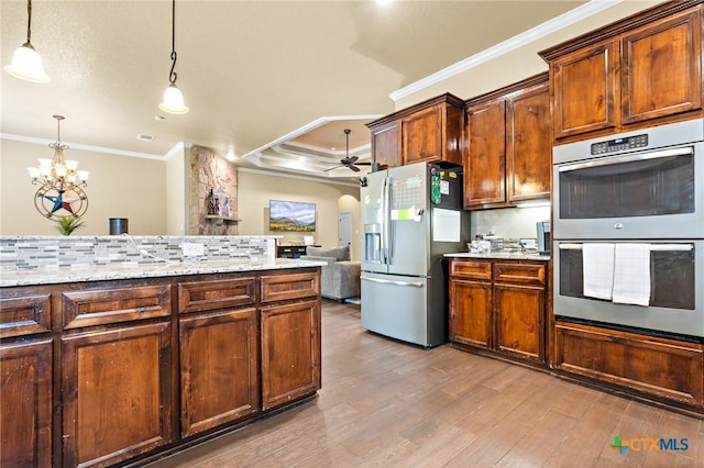 kitchen featuring tasteful backsplash, stainless steel appliances, a raised ceiling, and hanging light fixtures