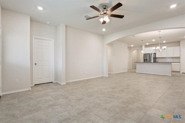 unfurnished living room with ceiling fan with notable chandelier