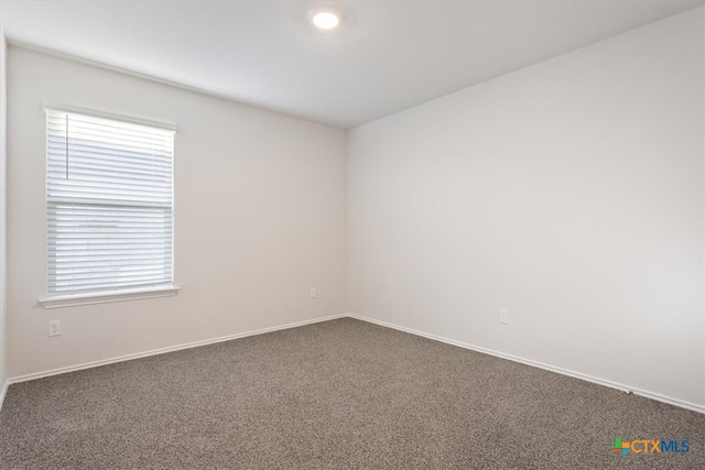 empty room featuring a wealth of natural light and dark carpet