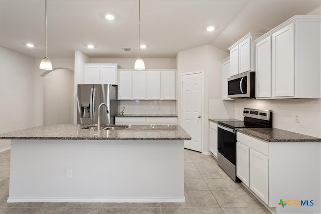 kitchen with appliances with stainless steel finishes, hanging light fixtures, a center island with sink, and sink